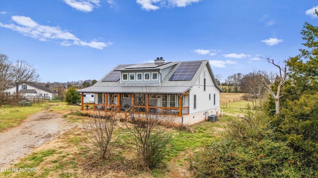 view of front of property with covered porch, solar panels, and central air condition unit