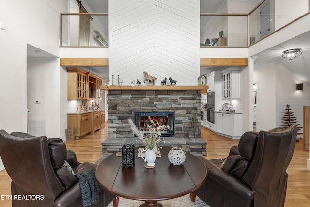 living room with a fireplace, high vaulted ceiling, and light hardwood / wood-style floors