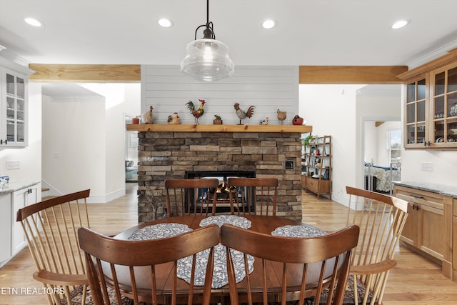 dining area featuring light hardwood / wood-style floors, crown molding, and a fireplace