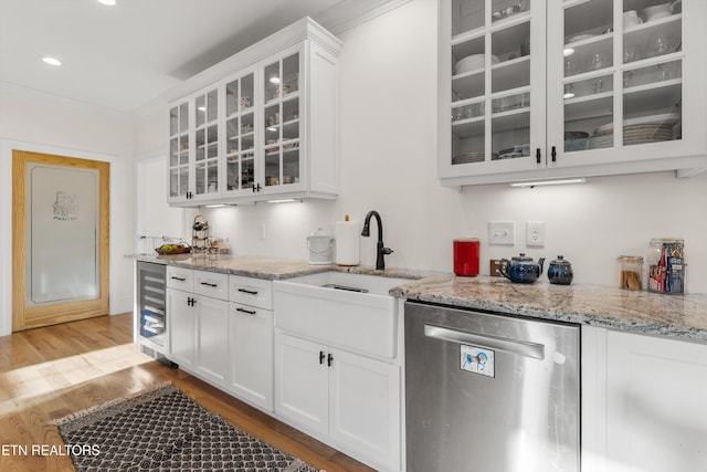 kitchen with light stone countertops, stainless steel dishwasher, ornamental molding, beverage cooler, and white cabinets