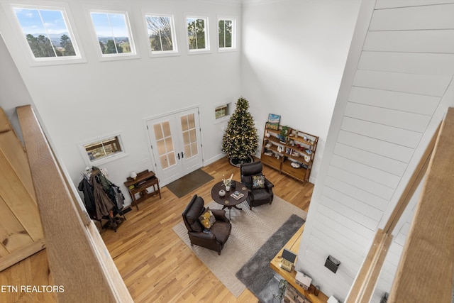 living room with french doors, a towering ceiling, and hardwood / wood-style flooring