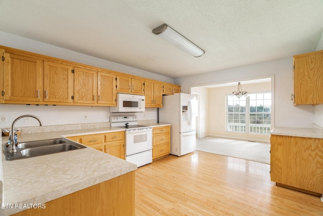 kitchen with light wood-type flooring, white appliances, a textured ceiling, sink, and a chandelier