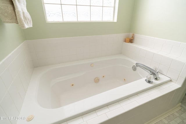 bathroom with a relaxing tiled tub and a healthy amount of sunlight