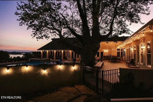 pool at dusk featuring an in ground hot tub