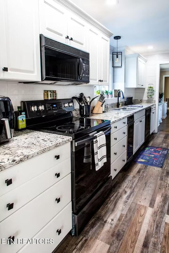 kitchen with dark wood-type flooring, black appliances, sink, hanging light fixtures, and white cabinetry