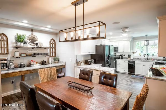 kitchen featuring light stone countertops, pendant lighting, dark wood-type flooring, and black appliances