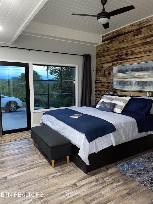 bedroom with hardwood / wood-style flooring, wood ceiling, ceiling fan, and wood walls