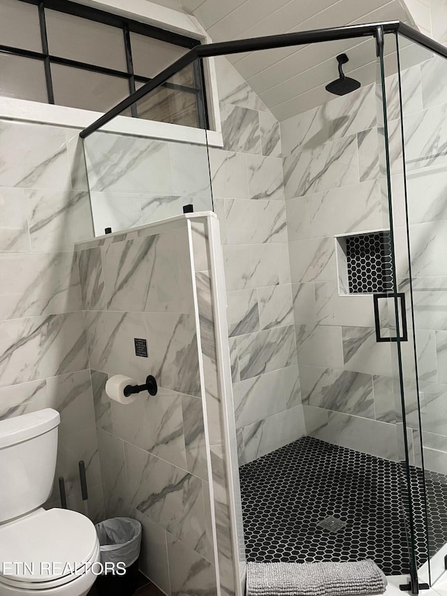 bathroom featuring toilet, walk in shower, and tile walls