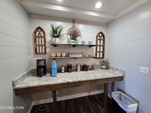 bar with dark hardwood / wood-style floors, light stone counters, and crown molding