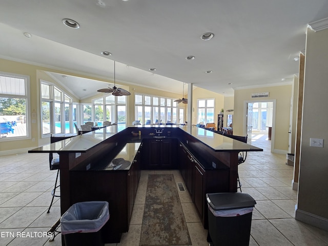 kitchen with ceiling fan, light tile patterned flooring, a kitchen bar, and lofted ceiling