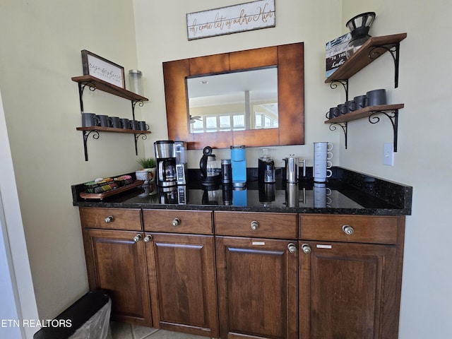 bar with dark brown cabinets and dark stone counters