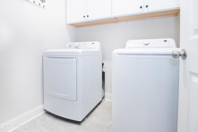 laundry room with cabinets, washing machine and dryer, and light tile patterned flooring