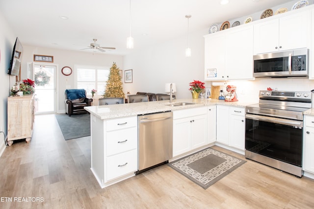 kitchen featuring sink, hanging light fixtures, stainless steel appliances, kitchen peninsula, and white cabinets