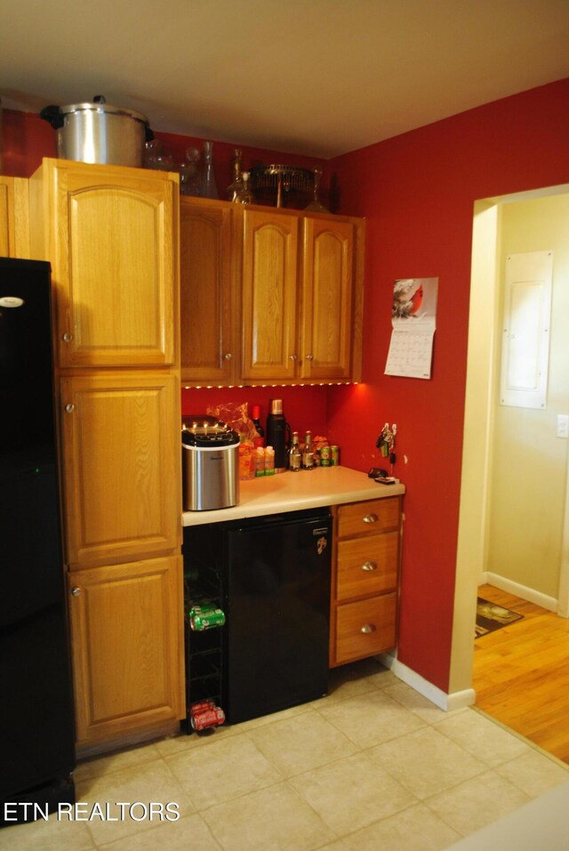 kitchen with electric panel, black fridge, and light hardwood / wood-style floors