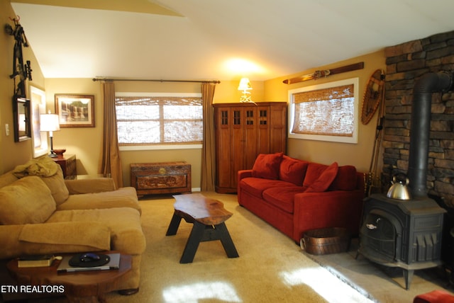 living room featuring a wood stove, light colored carpet, and lofted ceiling