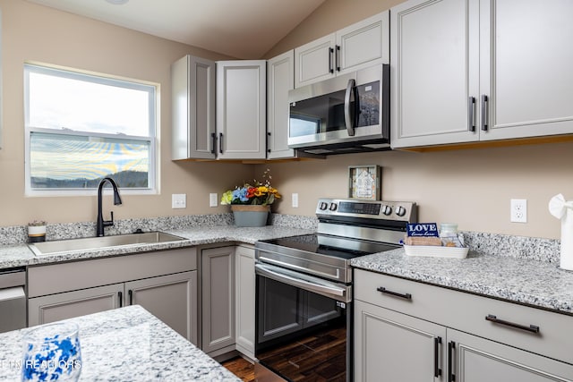 kitchen with light stone countertops, stainless steel appliances, dark wood-type flooring, and sink