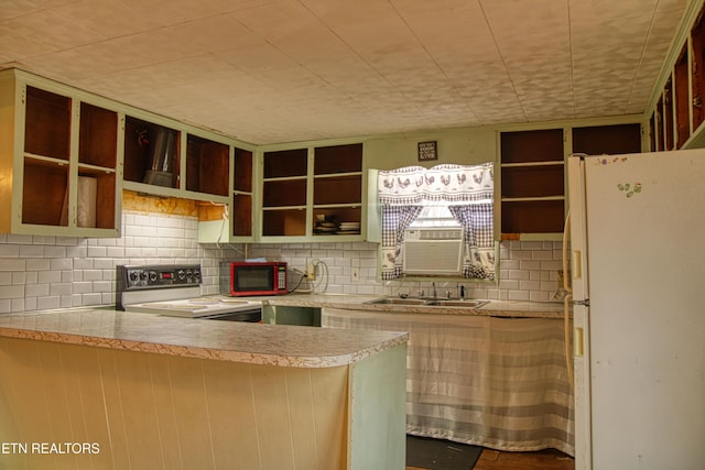 kitchen with sink, backsplash, kitchen peninsula, white fridge, and electric stove