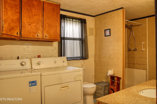 bathroom featuring vanity, a textured ceiling, tile walls, washing machine and dryer, and toilet