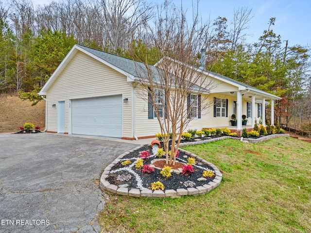 ranch-style home featuring covered porch, a front yard, and a garage