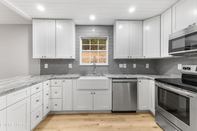 kitchen featuring white cabinetry, sink, light stone counters, and appliances with stainless steel finishes