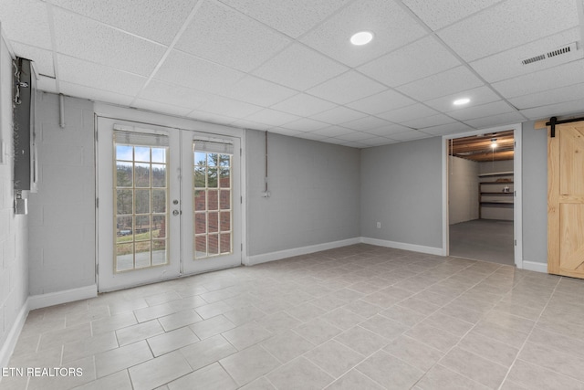 interior space featuring french doors, a barn door, and a drop ceiling