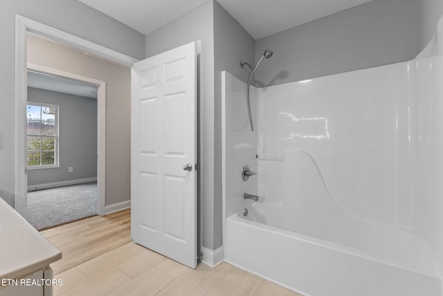 bathroom featuring vanity, hardwood / wood-style floors, a textured ceiling, and  shower combination