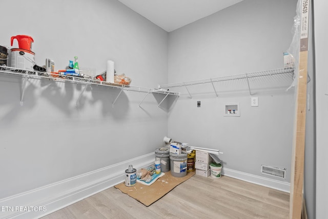 washroom featuring hookup for a washing machine, light hardwood / wood-style floors, and hookup for an electric dryer