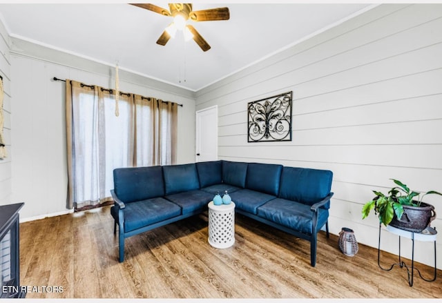 living room featuring crown molding, wooden walls, hardwood / wood-style floors, and ceiling fan