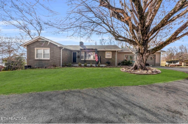 ranch-style home featuring a garage and a front lawn