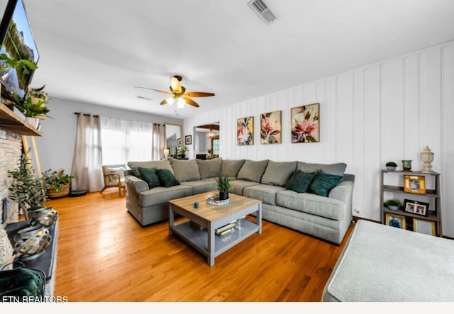 living room featuring hardwood / wood-style flooring, ceiling fan, and a fireplace