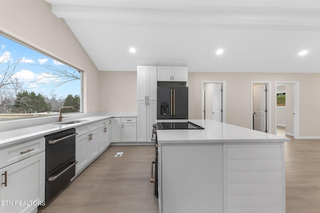 kitchen featuring stainless steel built in refrigerator, sink, a center island, light hardwood / wood-style floors, and white cabinetry