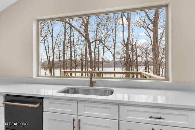 kitchen with light stone counters, white cabinetry, a healthy amount of sunlight, and sink