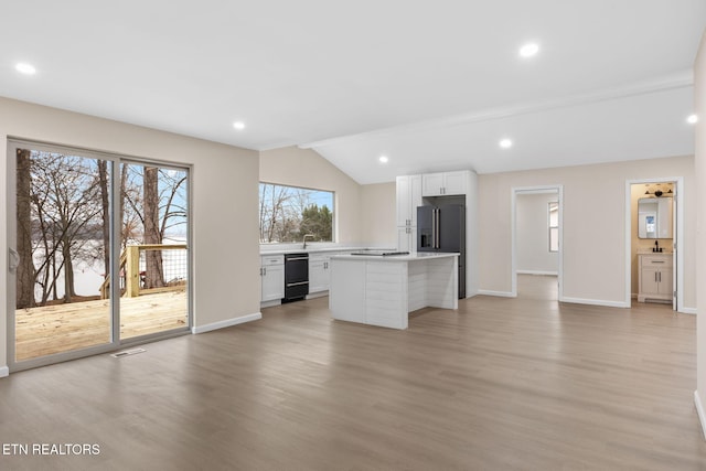 kitchen with black dishwasher, a center island, white cabinetry, and lofted ceiling