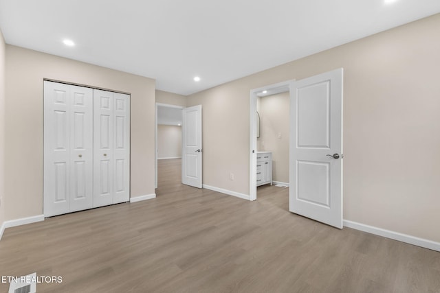 unfurnished bedroom featuring connected bathroom, light hardwood / wood-style floors, and a closet