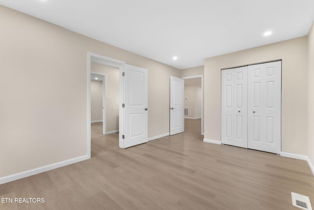 unfurnished bedroom with light hardwood / wood-style flooring and a closet