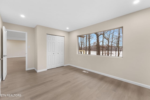 unfurnished bedroom with light hardwood / wood-style flooring and a closet