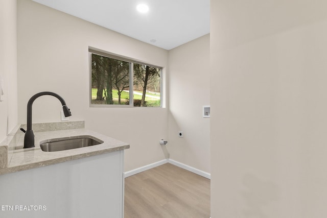 clothes washing area featuring electric dryer hookup, sink, washer hookup, and light hardwood / wood-style flooring