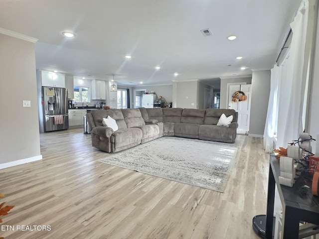 living room featuring crown molding and light hardwood / wood-style floors