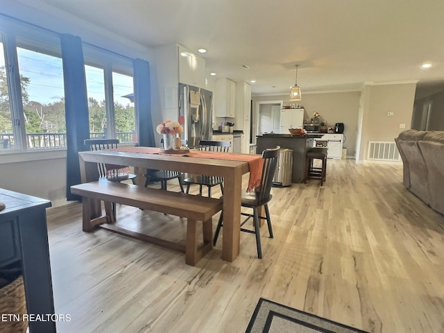 dining space featuring light wood-type flooring and ornamental molding