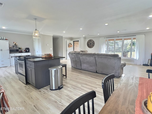 kitchen featuring pendant lighting, a kitchen island, ornamental molding, light hardwood / wood-style floors, and stainless steel appliances