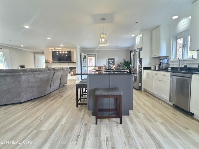 kitchen with a breakfast bar, decorative light fixtures, stainless steel appliances, and white cabinetry