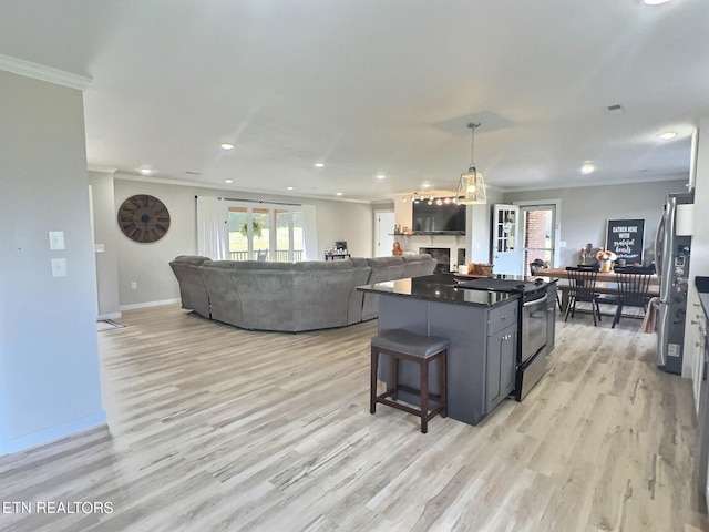 kitchen featuring black range with electric cooktop, light hardwood / wood-style flooring, crown molding, pendant lighting, and a breakfast bar area