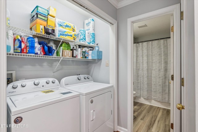 clothes washing area with light hardwood / wood-style floors, ornamental molding, and washing machine and clothes dryer