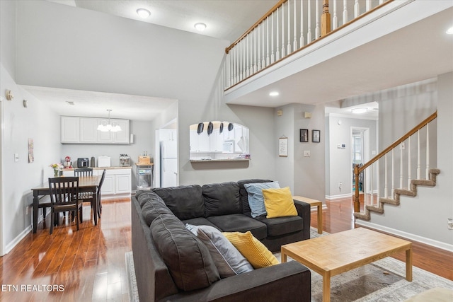 living room featuring hardwood / wood-style flooring, a notable chandelier, and a high ceiling