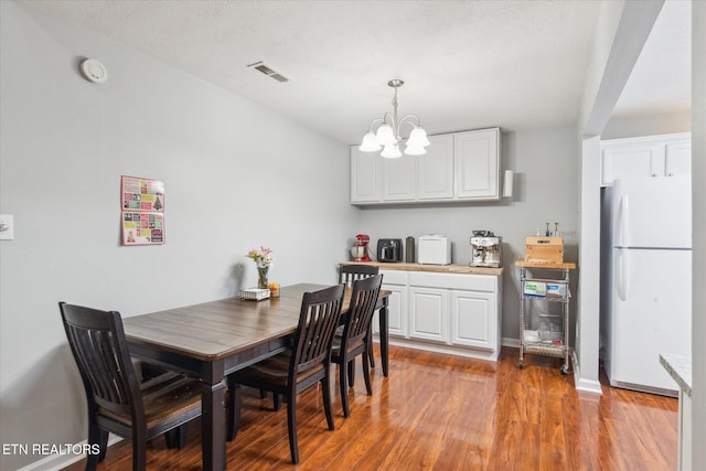 dining area with light hardwood / wood-style floors and an inviting chandelier