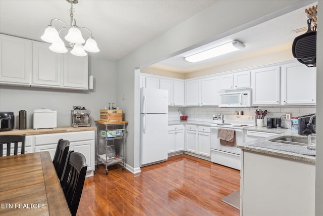 kitchen featuring white appliances, sink, decorative backsplash, decorative light fixtures, and white cabinetry