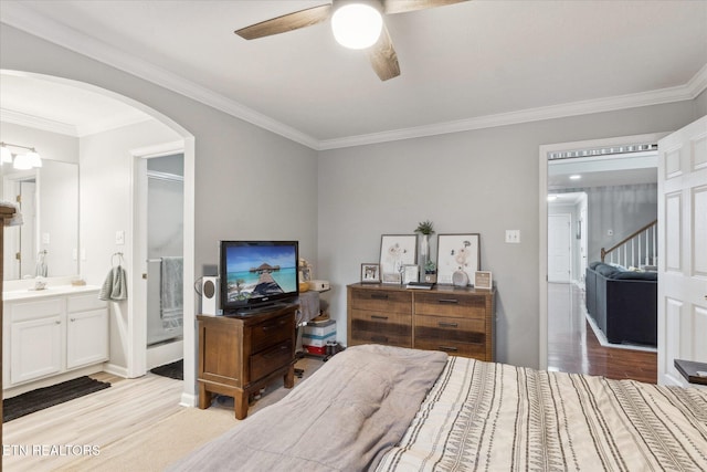 bedroom featuring ensuite bathroom, ceiling fan, light wood-type flooring, and crown molding