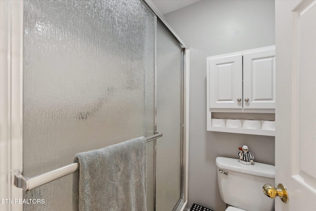 bathroom featuring toilet and a shower with door