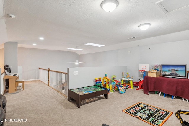 game room with ceiling fan, light colored carpet, and a textured ceiling