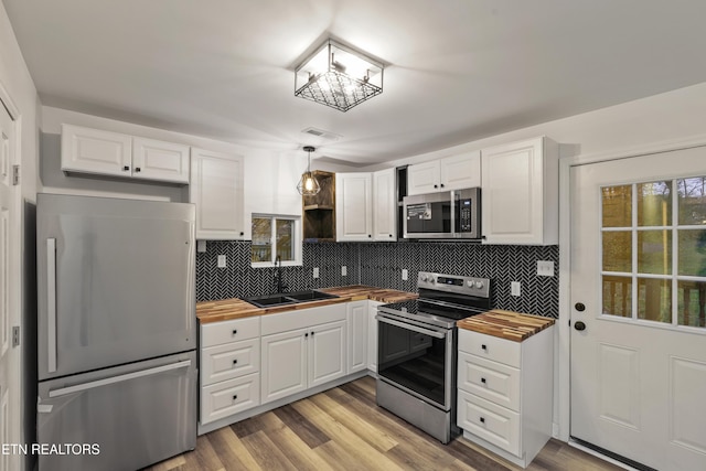 kitchen with white cabinets, pendant lighting, stainless steel appliances, and sink